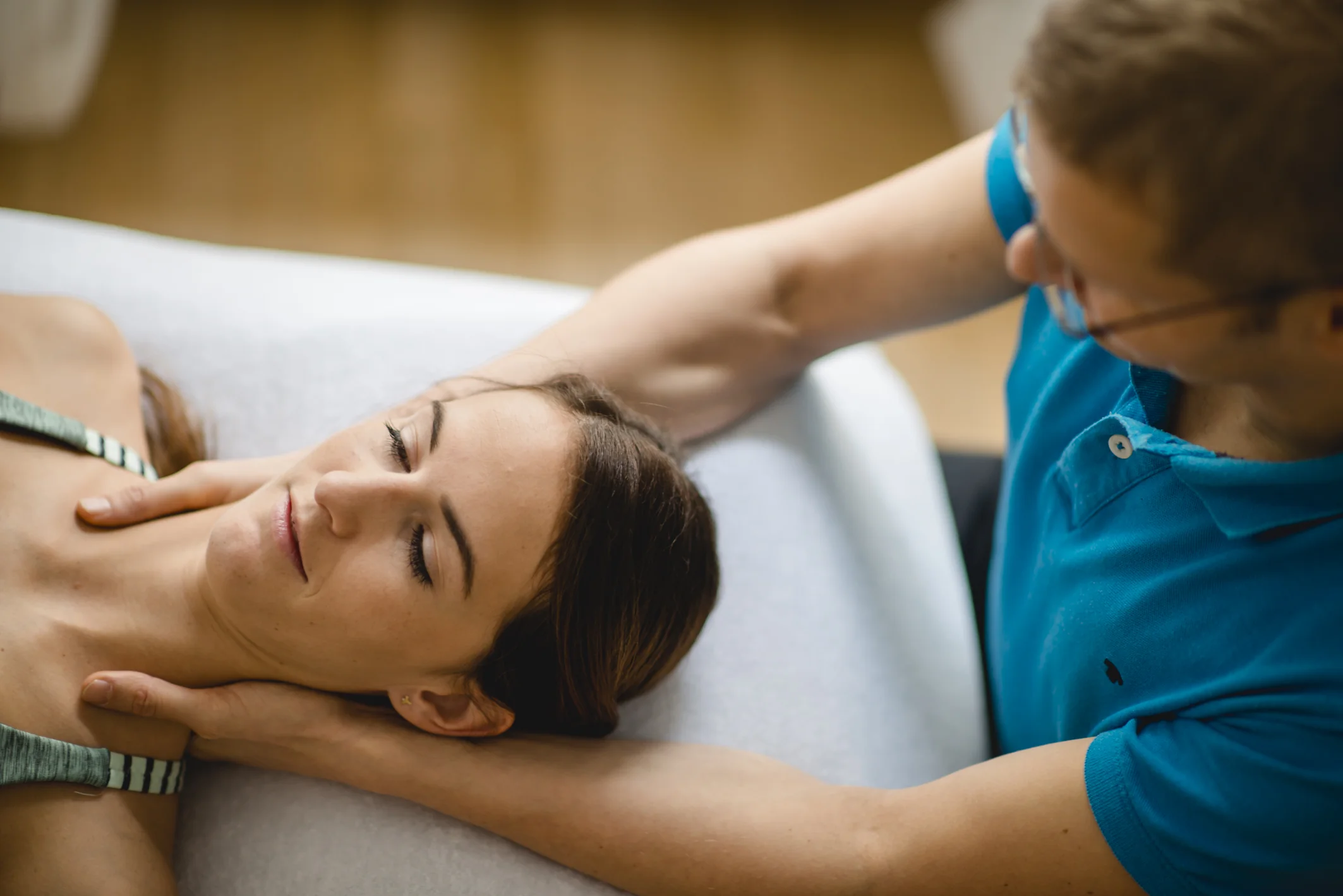 Jaap Switters führt manuelle Therapie am Nacken einer Patientin in seiner Sportphysiotherapie-Praxis in Wien durch